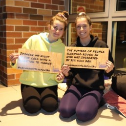 Two Vinnies Youth Members holding up Community Sleepout signs