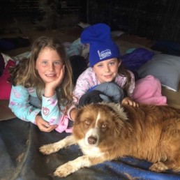 Two young girls sleeping out in their pyjamas and joined by a dog