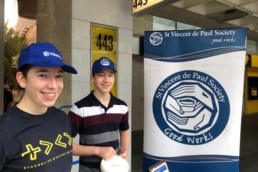 Vinnies Youth Members standing by a Vinnies banner and collecting money for Vinnies