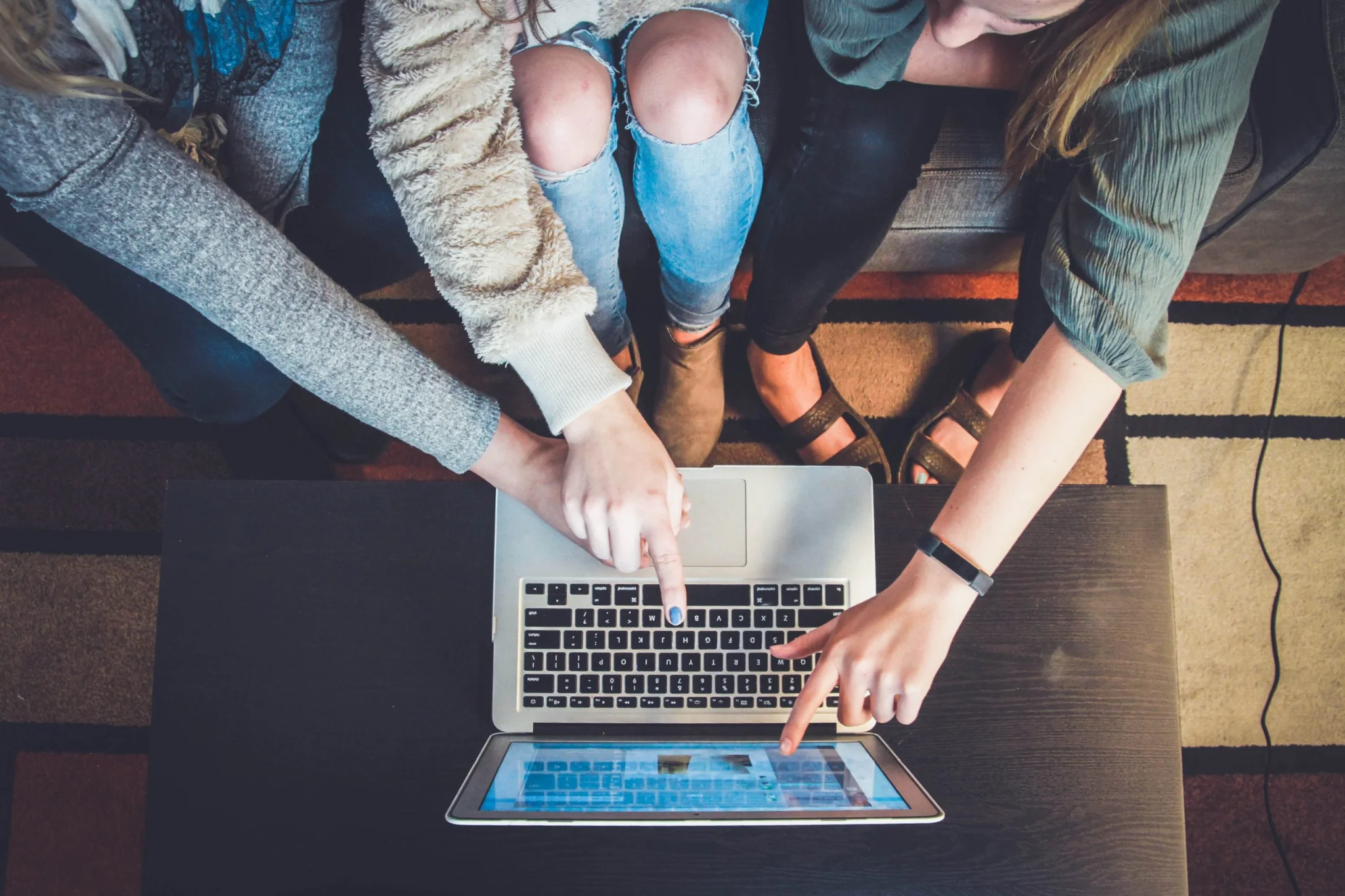Three young adults poiting to a laptop screen